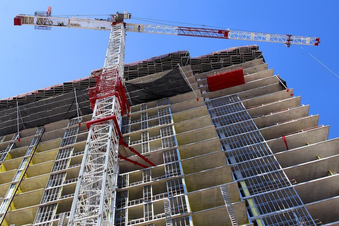 A tower crane rising over a high-rise under construction