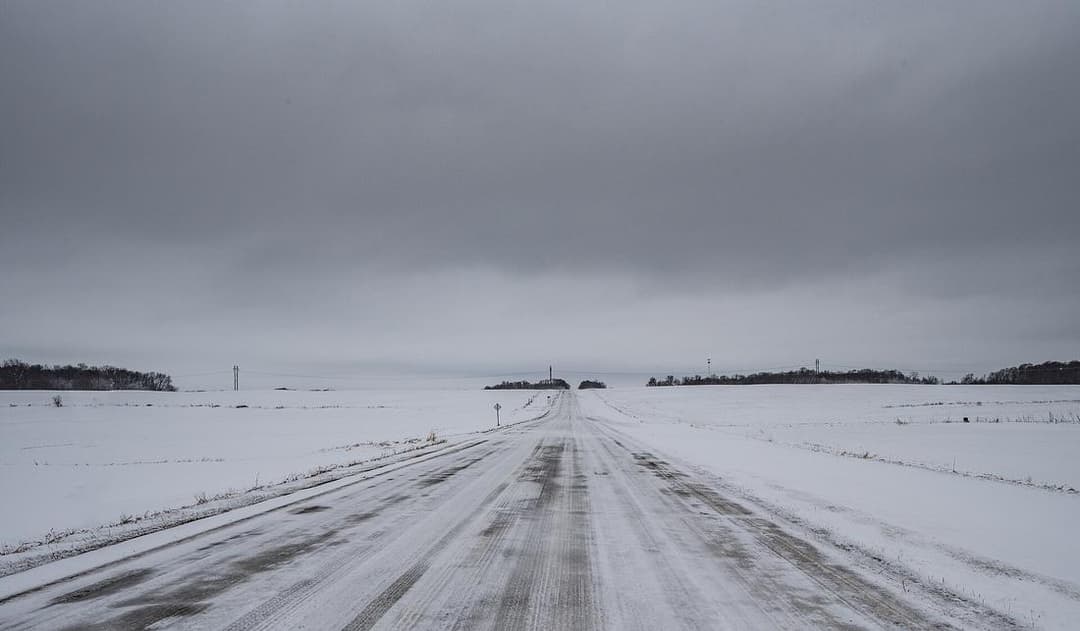 A snow-covered rural road between farms