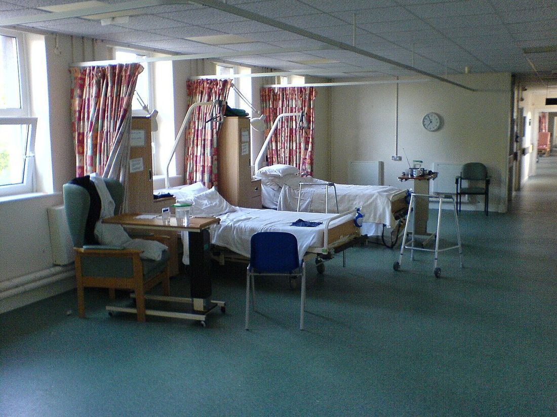 An empty hospital ward with beds and a walking frame