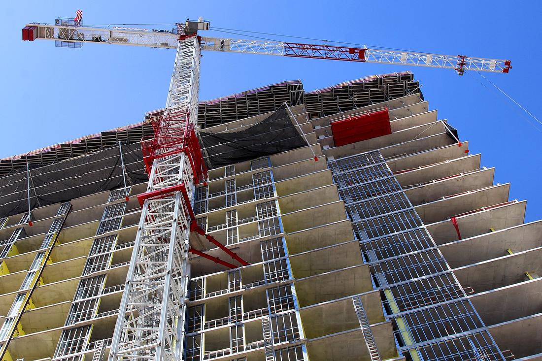 A tower crane rising over a high-rise under construction