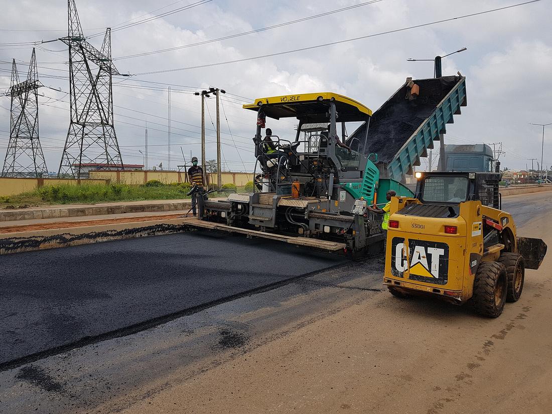 A crew paving a road with fresh asphalt