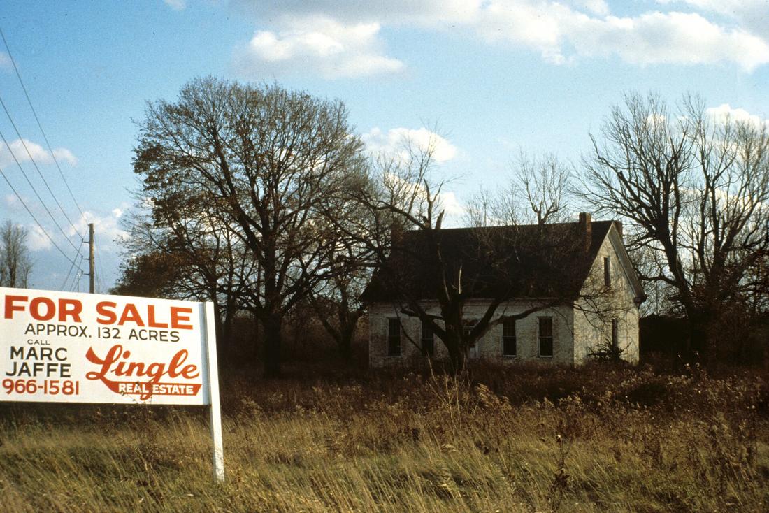 A for-sale sign in front of a rural property