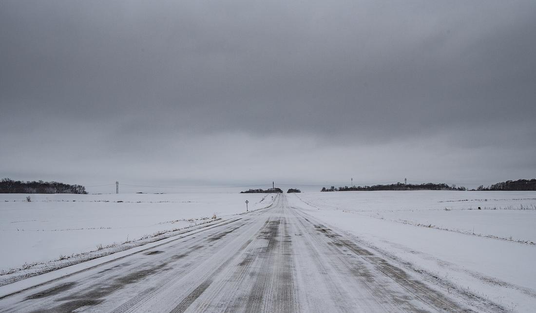 A snow-covered rural road between farms